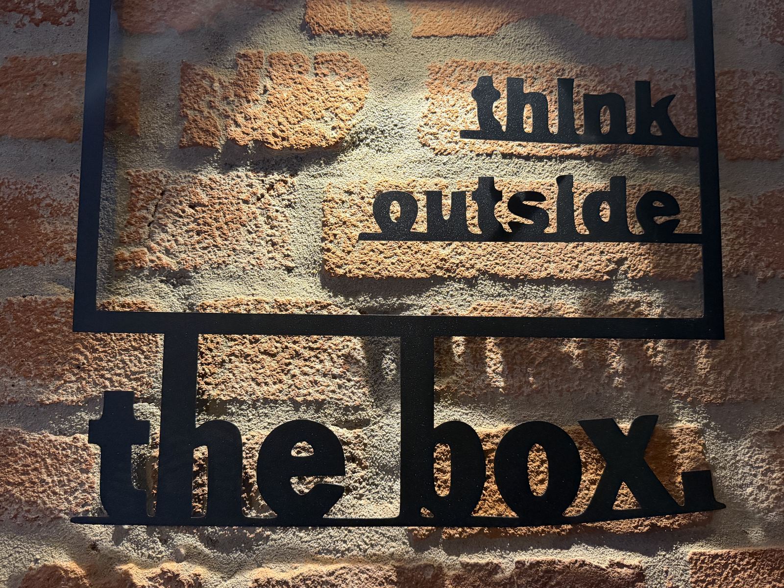 Wandschild „think outside the box“ an der Ziegelwand